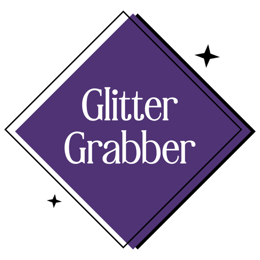 A purple diamond-shaped graphic with the words 'Glitter Grabber' in white serif text, outlined with black and white borders and small black sparkle icons on a white background.