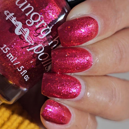 Closeup of nails painted in a lacquer that is bright red with an orange color shift and glitters.