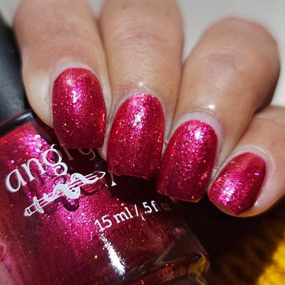Closeup of nails painted in a lacquer that is bright red with an orange color shift and glitters.
