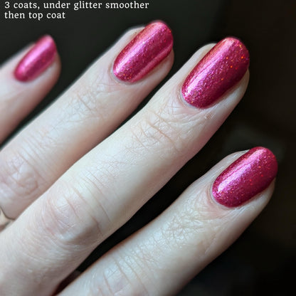 Closeup of nails painted in a lacquer that is bright red with an orange color shift and glitters.