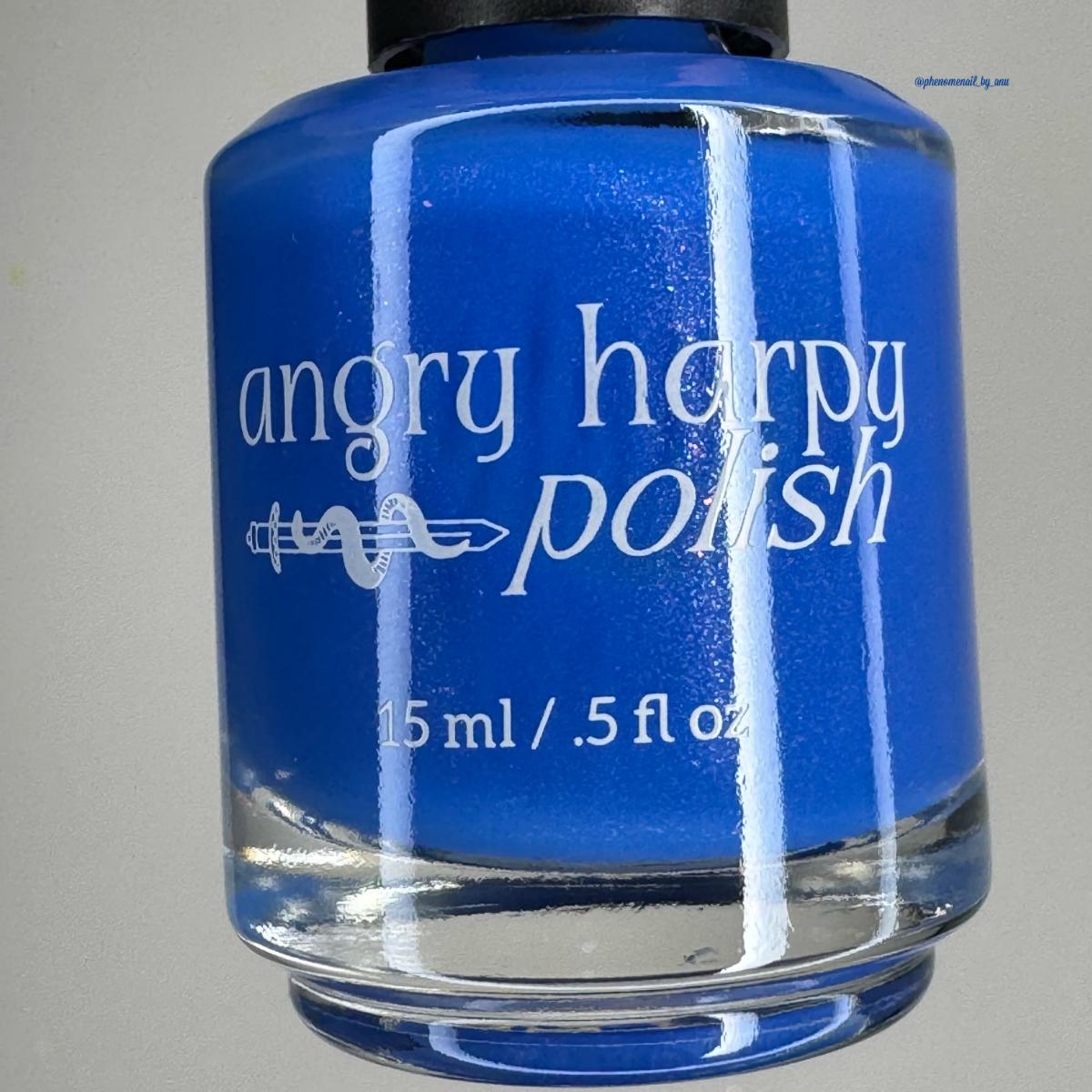 A bottle of nail polish with bright royal blue polish inside, featuring a black cap and white text that reads 'angry harpy polish' and '15 ml / .5 fl oz'.